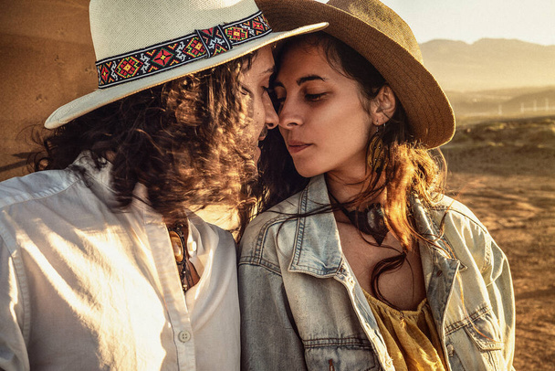 Beautiful couple in love, dating on the beach at sunset, kissing. Fashionable woman and man wearing boho hats. Summer lifestyle. Real people concept. - Fotó, kép