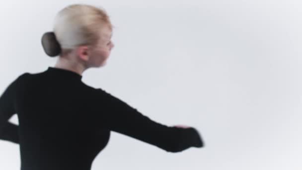 Balet - młoda blondynka kręcąca się w studio i patrząca w kamerę - Materiał filmowy, wideo