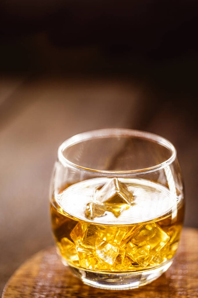 Whiskeyglas mit Eis, verschwommenem Hintergrund und Kopiertext - Foto, Bild