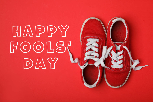 Shoes tied together on red background, flat lay. Happy Fool's Day - Fotografie, Obrázek