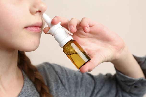 Sick little girl using nasal spray on beige background, closeup - Foto, Imagem