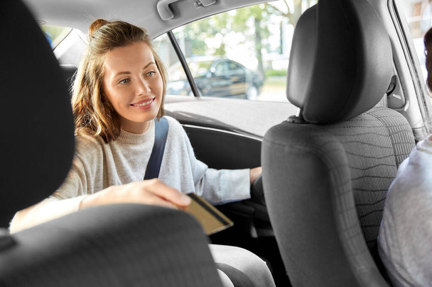 female passenger passing credit card to car driver - Foto, immagini