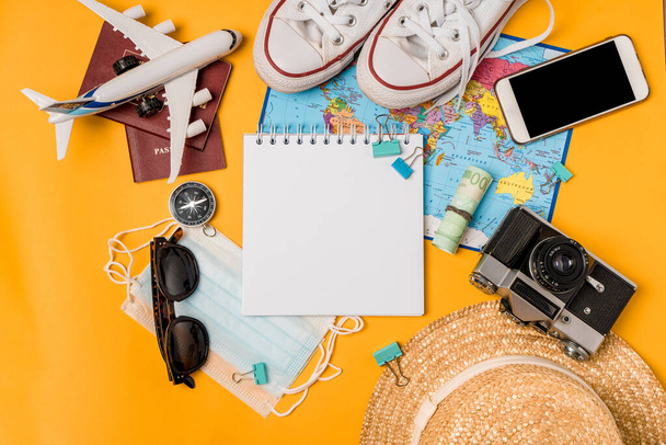 Sarı arkaplandaki seyahat aksesuarları üzerine metin yazmak için boşluk olan bir defter aç. Yaz tatilini, seyahatini ve tatilini planlıyorsun. Bir blog yazarı, bir gezgin için bir set. - Fotoğraf, Görsel