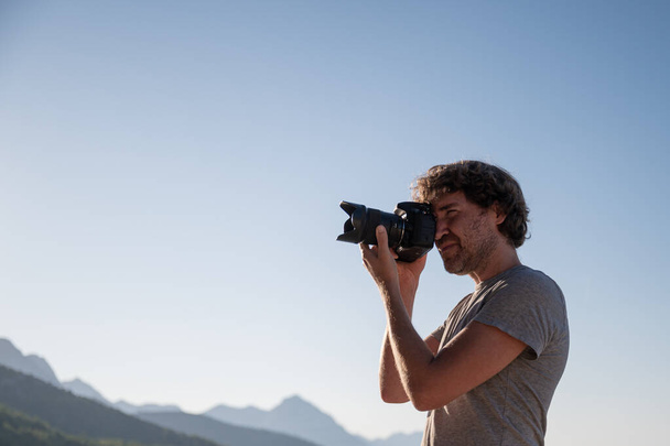 Young man taking photos with professional dslr camera outside on a beautiful summer morning. - Valokuva, kuva