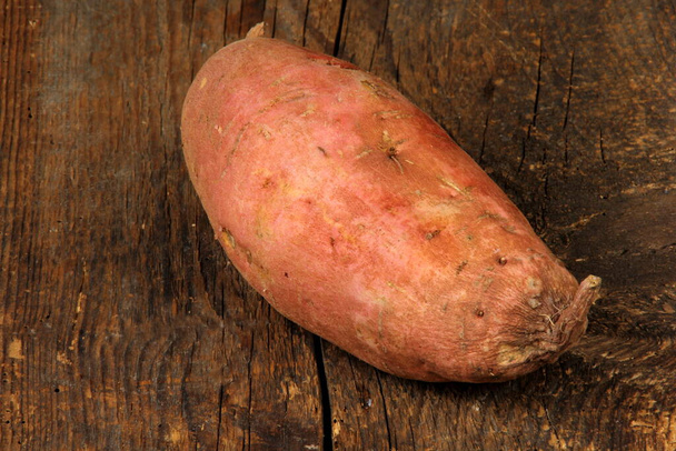 Syrové sladké brambory nebo batáty na staré dřevěné desce. Batata na dřevěném povrchu - Fotografie, Obrázek