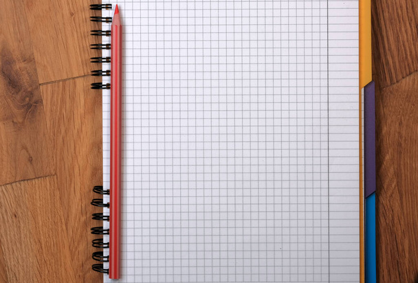 Tahta bir arka plan üzerinde kırmızı bir kalem ile kare kağıtlar için yırtık not defterini aç - Fotoğraf, Görsel