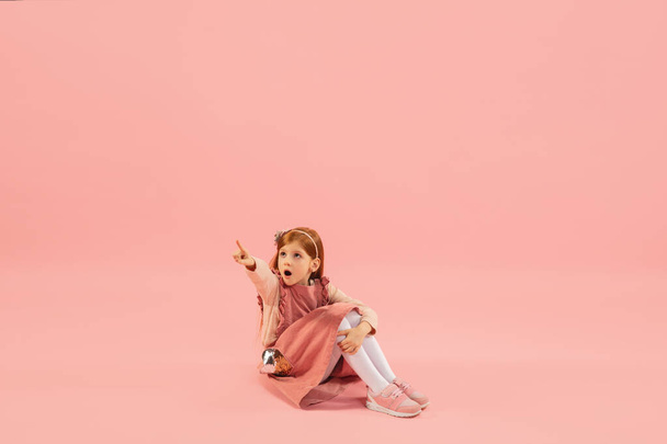 Childhood and dream about big and famous future. Pretty longhair girl isolated on coral pink background - Foto, afbeelding