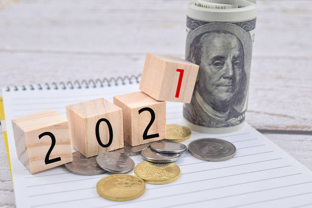 Imagem de foco seletivo de nota bancária, moeda e 2021 formulação em bloco de madeira. Conceito de economia - Foto, Imagem