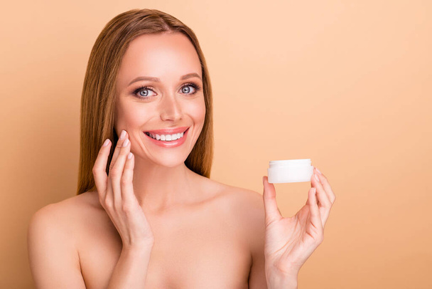 Close-up view portrait of her she nice-looking attractive lovely cheerful cheery sweet girl holding in hand night new useful cream product novelty advice advert isolated over beige pastel background - 写真・画像