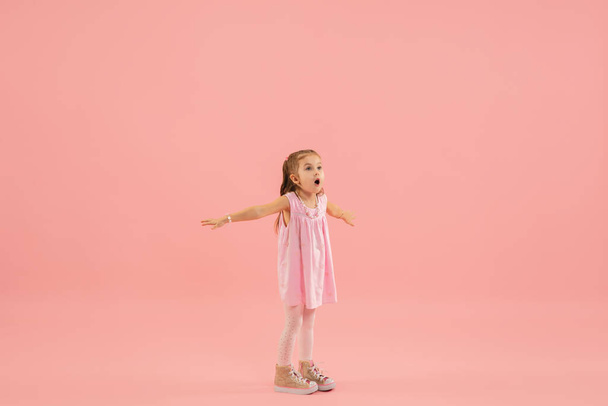 Childhood and dream about big and famous future. Pretty longhair girl isolated on coral pink background - Fotoğraf, Görsel