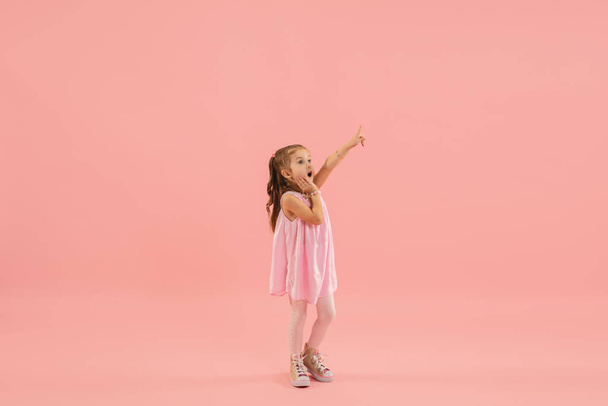 Childhood and dream about big and famous future. Pretty longhair girl isolated on coral pink background - Foto, imagen