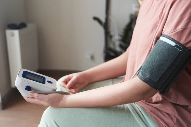 uma jovem mede sua pressão arterial com um tonômetro  - Foto, Imagem