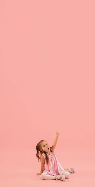 Childhood and dream about big and famous future. Pretty longhair girl isolated on coral pink background - Foto, immagini