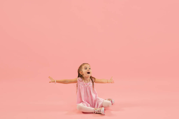 Childhood and dream about big and famous future. Pretty longhair girl isolated on coral pink background - Valokuva, kuva