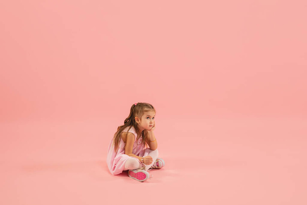Childhood and dream about big and famous future. Pretty longhair girl isolated on coral pink background - Fotografie, Obrázek