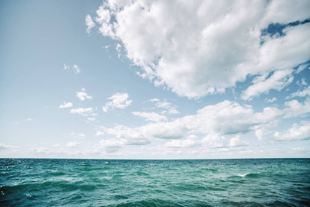 Água azul-turquesa em um mar nórdico frio sob um céu azul com nuvens brancas - Foto, Imagem