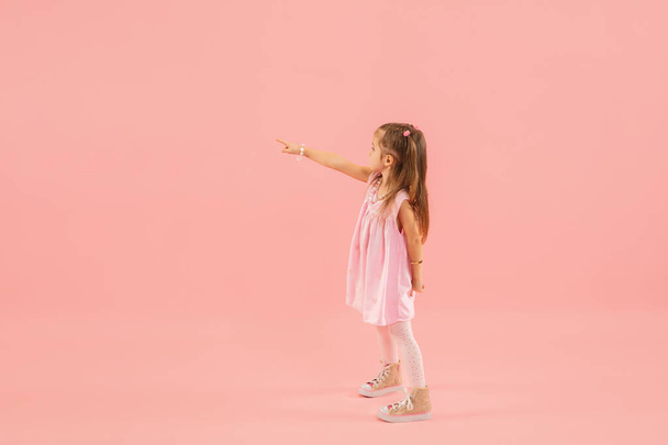 Childhood and dream about big and famous future. Pretty longhair girl isolated on coral pink background - Φωτογραφία, εικόνα