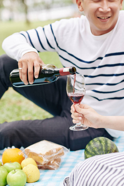 Cropped image of man pouring red wine in glass for his girlfriend at date - Photo, Image