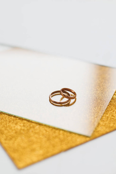 Two golden wedding rings on a golden background - Foto, afbeelding