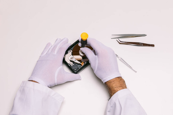 Hands of a technician with gloves repairing a hard drive. Technology maintenance concept - Foto, Bild
