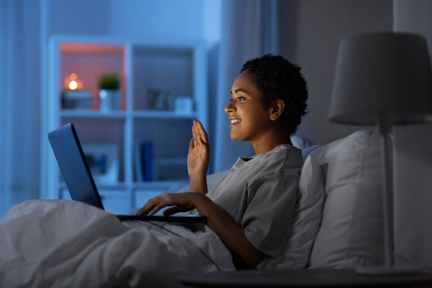 woman having video call on laptop in bed at night - Foto, Bild