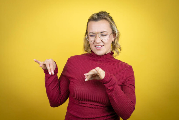 Young caucasian woman wearing casual red t-shirt over yellow background disgusted expression, displeased and fearful doing disgust face because aversion reaction. Annoying concept - Photo, Image