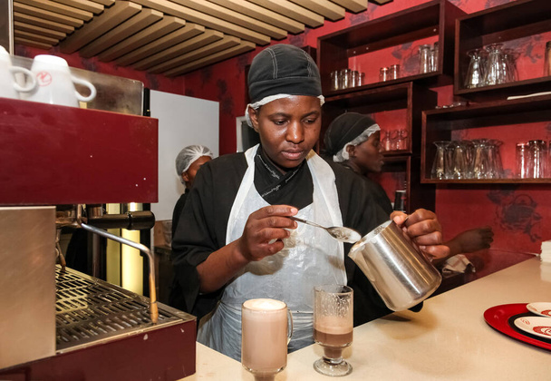 Johannesburg, South Africa - August 7, 2012: African Female barista making a hot beverage in a coffee shop - 写真・画像