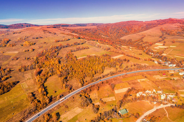 Panoramic aerial view of the mountain highway and village in autumn. Beautiful skyview countryside landscape. Carpathian mountains. Ukraine - Fotografie, Obrázek