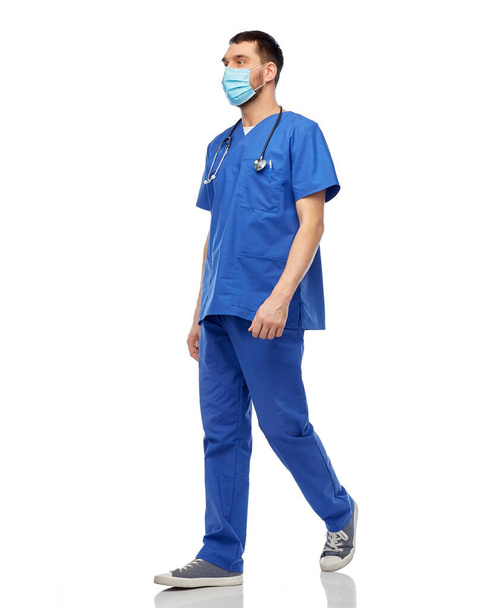 male doctor in blue uniform and mask walking - Fotoğraf, Görsel