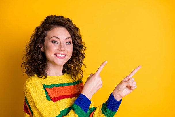 Photo portrait of cheerful girl pointing two fingers at blank space isolated on bright yellow colored background - Photo, Image