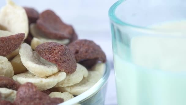 chocolade cornflakes in een kom en melk op tafel  - Video