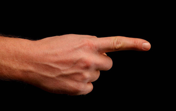 Hand und Finger zeigen auf etwas auf schwarzem Hintergrund - Foto, Bild