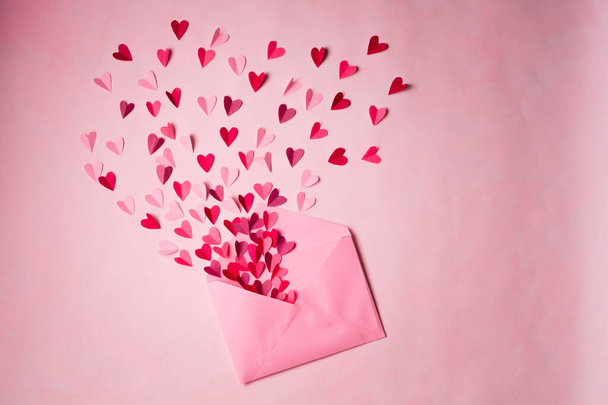 Love letters. Pink  envelope with  red hearts inside on  pink background. - Fotoğraf, Görsel