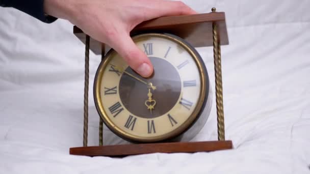 La mano masculina sostiene el reloj de mesa de madera clásico vintage con números romanos. 4K - Imágenes, Vídeo