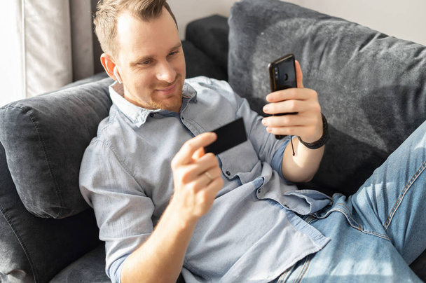 A guy holding credit card, using smartphone - Photo, image