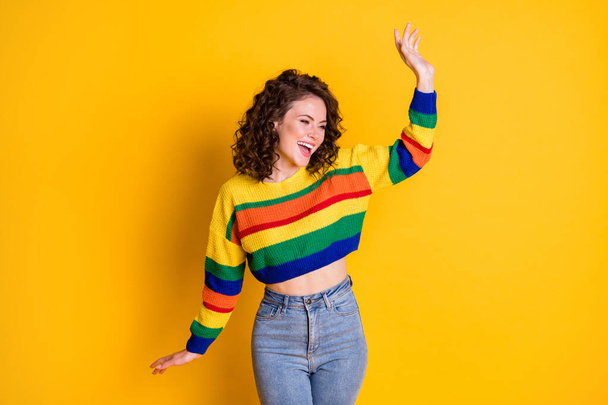 Photo of careless charming lady raise hand dance wear striped cropped sweater jeans isolated yellow color background - 写真・画像