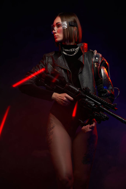 Mujer militar con gafas y rifle posando en fondo oscuro - Foto, imagen