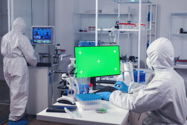 Técnico de laboratorio en laboratorio de medicina utiliza ordenador con pantalla verde - Foto, Imagen