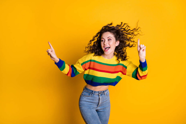 Photo of funny shiny lady wearing casual colorful sweater dancing looking pointing empty space isolated yellow color background - Foto, afbeelding