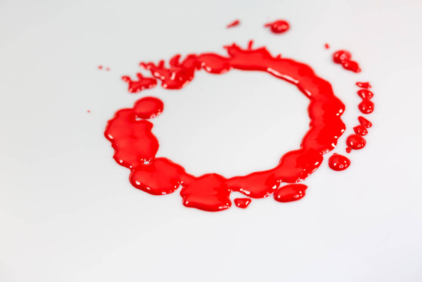 Κόκκινο μελάνι στάζει κύκλους στο έδαφος ενός περιστρεφόμενου λευκού αντικειμένου. - Φωτογραφία, εικόνα
