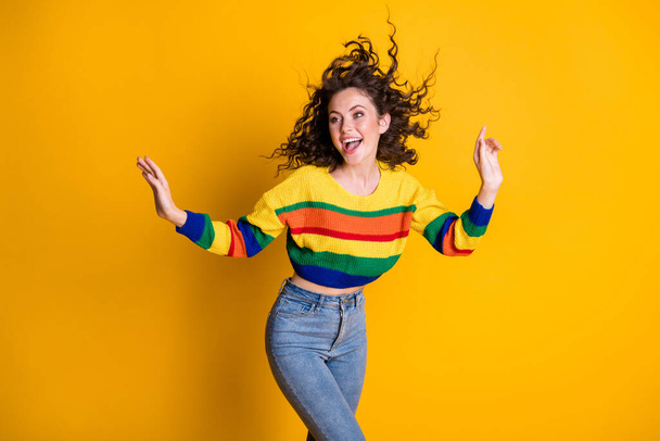Photo of sweet shiny woman dressed casual colorful sweatshirt dancing looking pointing hand arm empty space isolated yellow color background - Zdjęcie, obraz
