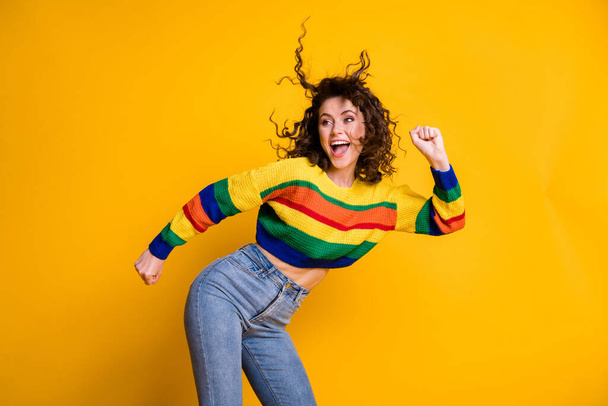 Photo of shiny funny woman dressed casual colorful sweatshirt dancing looking empty space hands arms fists isolated yellow color background - Foto, Imagem