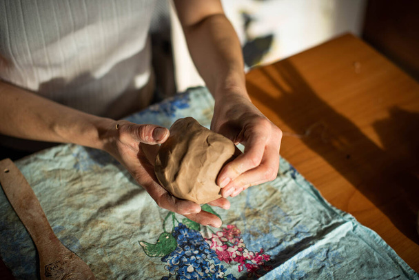La poterie. Une fille avec une ficelle dans les mains coupe la couche supérieure de l'argile motte. Le processus de modélisation des articles céramiques. - Photo, image