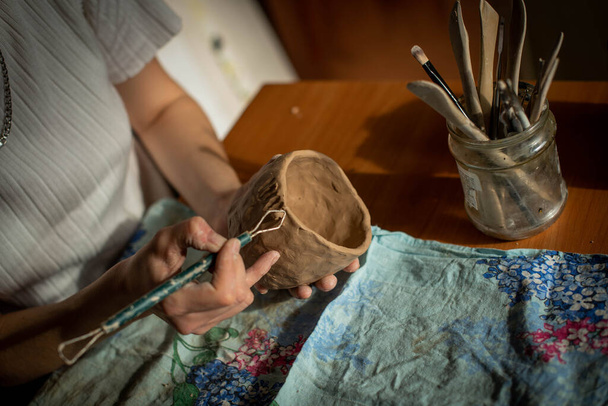 Töpferei. Ein Mädchen mit einer Schnur in der Hand schneidet die oberste Schicht von Schlehm ab. Der Prozess der Modellierung von Keramik. - Foto, Bild