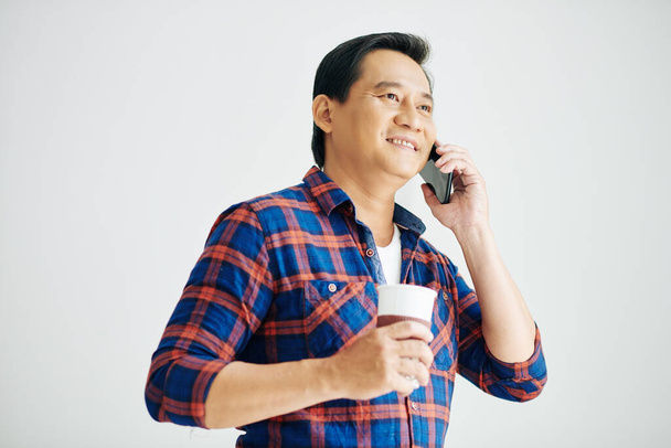 Portrait d'un homme mature positif buvant du café et appelant au téléphone - Photo, image
