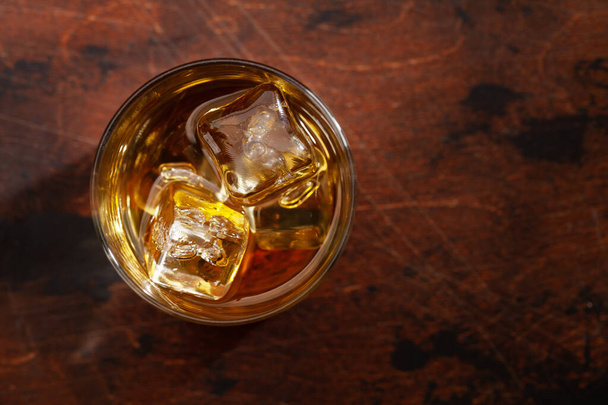 vaso de whisky escocés sobre mesa de madera. Con espacio para copias. Vista superior plano laico - Foto, Imagen