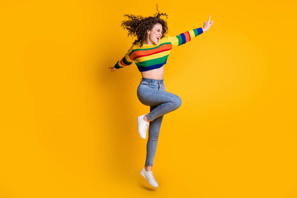 Full length photo of energy jumping lady wearing casual colorful sweater dancing pointing looking empty space isolated yellow color background - Zdjęcie, obraz
