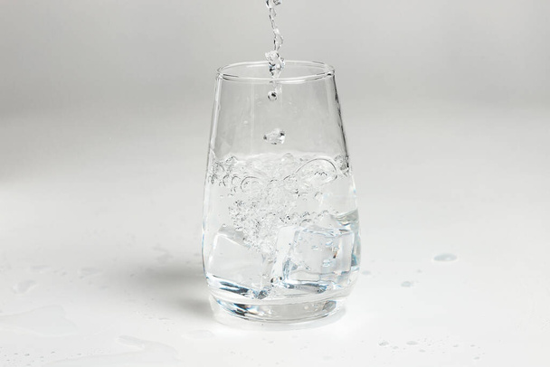 clean water is poured into a glass cup. ice in a glass. - Фото, зображення