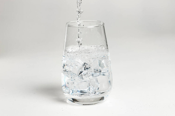 clean water is poured into a glass cup. ice in a glass. - Foto, immagini