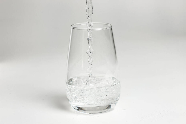 clean water is poured into a glass cup. - Zdjęcie, obraz